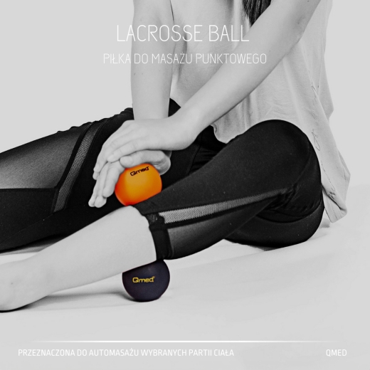 Kobieta w legginsach wykonująca automasaż nóg przy użyciu dwóch piłek do masażu punktowego Qmed w kolorze pomarańczowym i czarnym